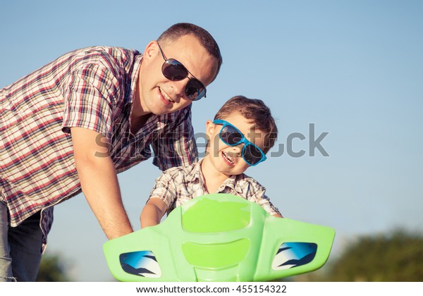 Father and son playing on the road at\
the day time. They driving on quad bike in the park. People having\
fun on the nature. Concept of friendly\
family.