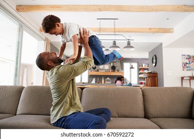 Father And Son Playing On Sofa In Lounge Together
