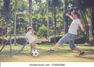 Father And Son Playing In The Park  At The Day Time. Concept Of Friendly Family. Picture Made On The Green Meadow.