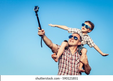 Father and son playing in the park  at the day time. Concept of friendly family. Picture made on the background of blue sky.