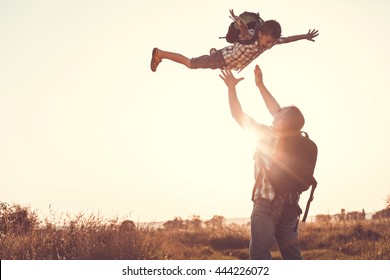 Father And Son Playing In The Park At The Sunset Time. People Having Fun On The Field. Concept Of Friendly Family And Of Summer Vacation.