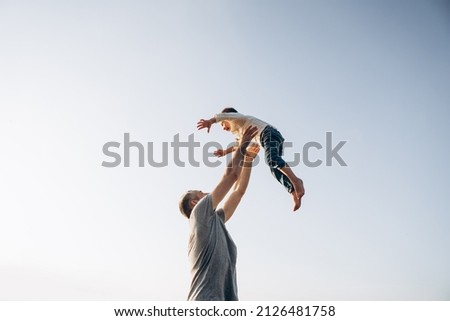 Father and son playing in the park at the sunset time. Family, trust, protecting, care, parenting, summer vacation concept