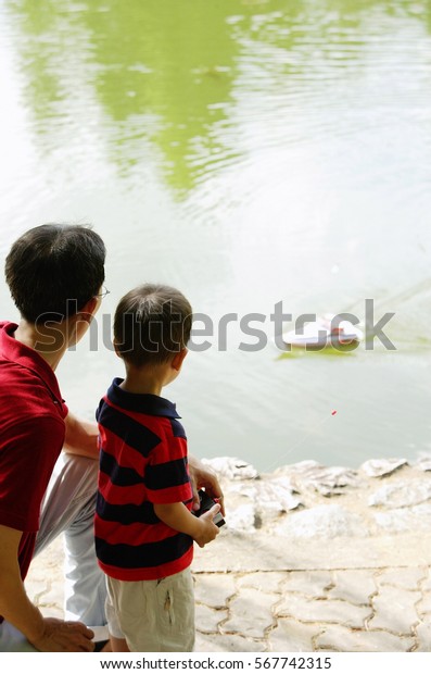 Father and son\
playing with remote control\
boat