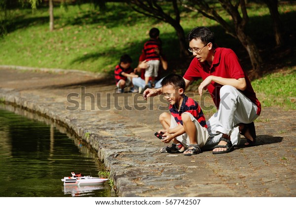 Father with\
son, playing with remote control\
boat