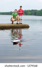 Father And Son Playing With A Remote Controlled Boat