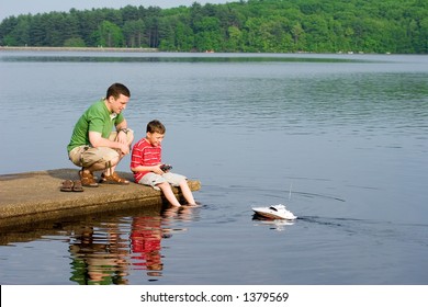 Father And Son Playing With A Remote Controlled Boat