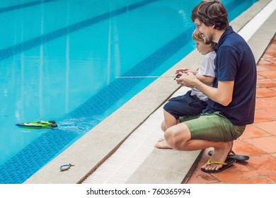 Father And Son Playing With A Remote Controlled Boat In The Pool.