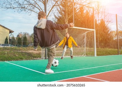 Father And Son Playing Soccer Ball On Playground, Dad Teaches Son To Play On Football Field, Family Weekend Activities.