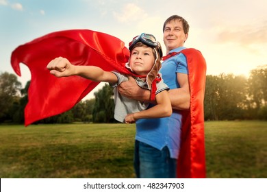 Father and son playing in superhero costumes in the park on nature. A happy family. Father's Day.