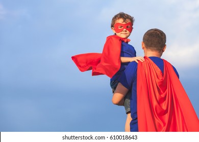 Father and son playing superhero at the day time. People having fun outdoors. Concept of friendly family.