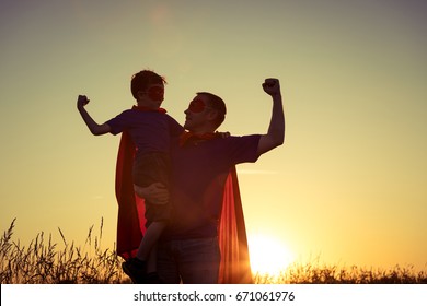Father and son playing superhero at the sunset time. People having fun outdoors. Concept of friendly family.