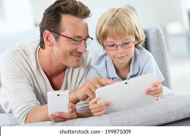 Father and son playing with tablet and smartphone - Powered by Shutterstock