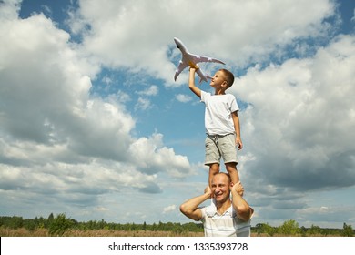 father and son playing with a toy airplane outdoors