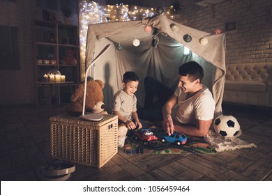 Father and son are playing with toy cars on carpet road in blanket fort at night at home. - Powered by Shutterstock