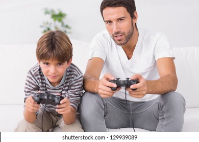 Father And Son Playing Video Games On The Couch