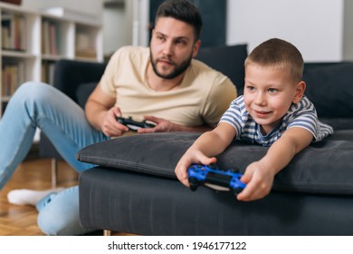 father and son playing video games at home - Shutterstock ID 1946177122