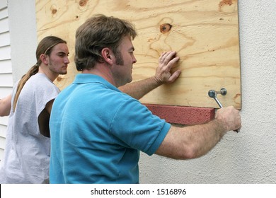 A father & son preparing for a hurricane by putting plywood over the windows.