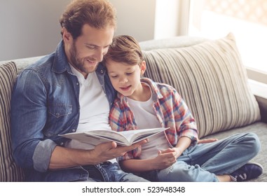Vater und Sohn lesen ein Buch und lächeln, während sie zu Hause Zeit zusammen verbringen