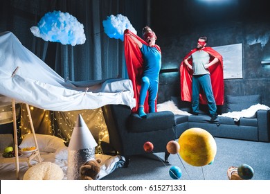father and son in red superhero costumes playing at home 
