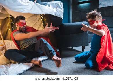 father and son in red superhero costumes playing at home
