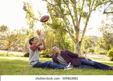 Father And Son Relax, Throwing American Football In A Park