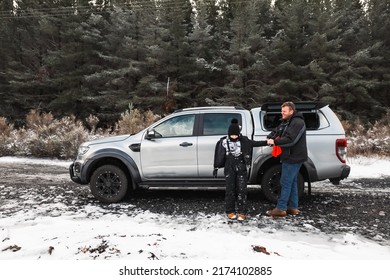 Father And Son Removing Snow Gear At Vehicle After Fun In The Snow