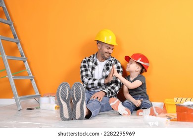 Father and son with repair tools near orange wall - Powered by Shutterstock