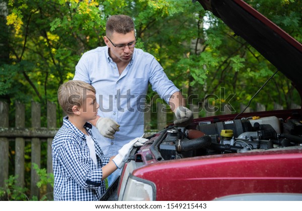 Father and son are repairing the car outdoors.\
Auto repair concept.