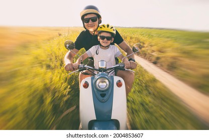 The father and son riding together through the field by pathway on the retro scooter - Powered by Shutterstock