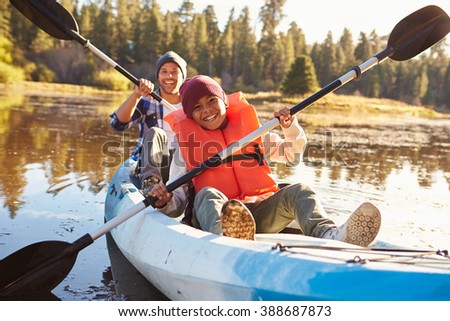 Father And Son Rowing Kayak On Lake
