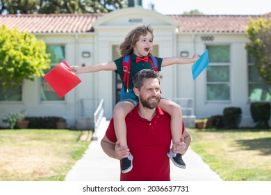 Father And Son Run With Father After Come Back From School. School, Family, Education And Outdoor Concept, First Day Of Fall. Dad And Son Having Fun Near School Yard. Concept Of Friendly Family.