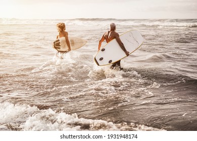 Father and son running on the beach at sunset for surf training - Focus on right man - Powered by Shutterstock