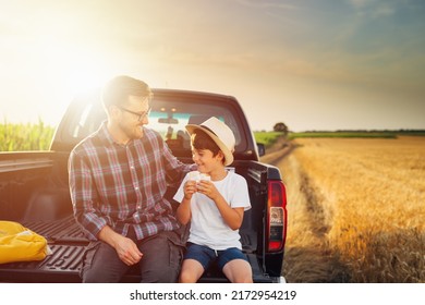 Father And Son Sits On Truck Trunk Outdoor On Field