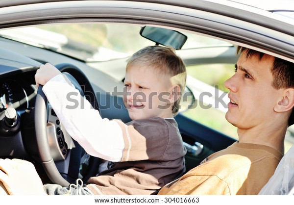 Father and son are  sitting\
in a car