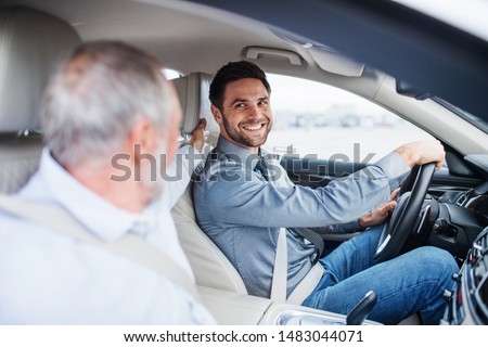 Father and son sitting in car, driving and talking.