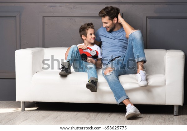 Father and son are\
sitting on the couch
