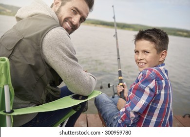 Father And Son Sitting On The Pier And Fishing
