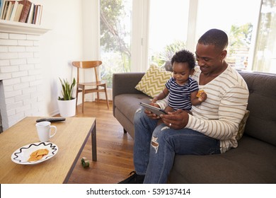 Father And Son Sitting On Sofa At Home Using Digital Tablet - Powered by Shutterstock