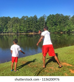 Father And Son Skip Rocks On The Lake