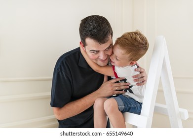 Father and son are smiling while spending time together. Little boy is sitting on a stepladder. Closeup