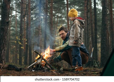 Father and son spending happy leisure time together outdoors in forest trees background. Family man child making campfire on nature woods. Relations happiness activity holidays vacation journey  - Powered by Shutterstock