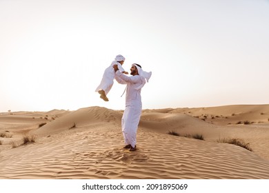 Father and son spending time in the desert on a safari day. Arabian family from the emirates wearing the traditional white dress. Concept about lifestyle and middle eastern cultures - Powered by Shutterstock