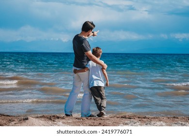 Father and son standing on the shore of the lake and looking away - Powered by Shutterstock