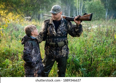 Father And Son Standing Together Outdoors With Shotgun Hunting Gear.