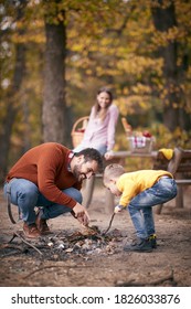 Father And Son Starting A Fire Together On A Camping; Quality Family Time Concept