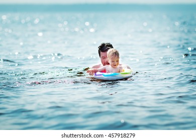 Father And Son Swimming At The Sea. Man With A Child Having Fun In The Water