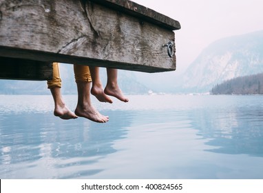Father and son swung their legs from the wooden pier on mountain lake