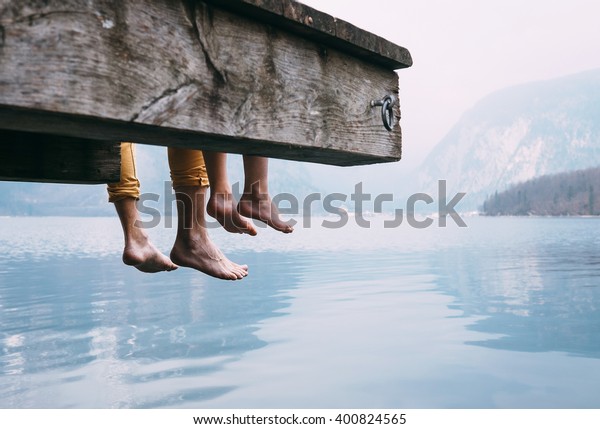 Father and son swung their legs from the wooden pier\
on mountain lake