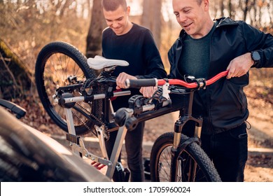 Father And Son Take The Bike Down From The Rack On The Car