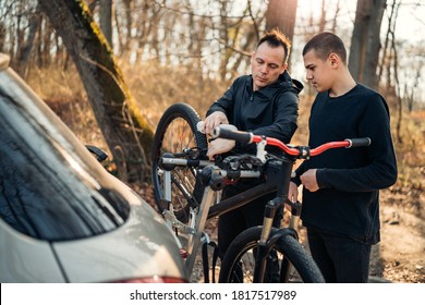 Father And Son Take The Bike Down From The Rack On The Car